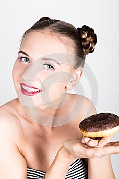 Girl in bright makeup eating a tasty donut with icing. Funny joyful woman with sweets, dessert. dieting concept. junk