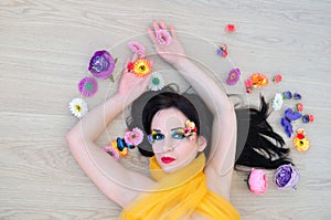 Girl with bright makeup lies in the flowers