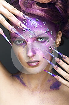 Girl with bright purple creative makeup with crystals and long nails. Beauty face.