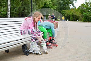 Girl with brother sitting in the Park on a bench and put on roll