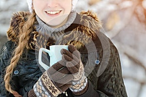 Girl in the brown gloves holding a blue mug of tea, part of the