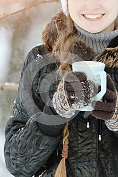 Girl in the brown gloves holding a blue mug of tea, part of the