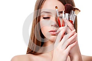 Girl with brown hair holding set of makeup brushes