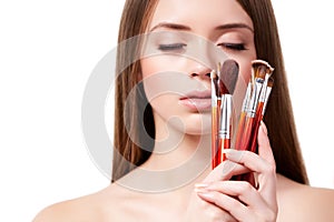 Girl with brown hair holding set of makeup brushes