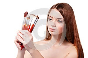 Girl with brown hair holding set of makeup brushes