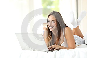 Girl browsing in a laptop in the bedroom photo