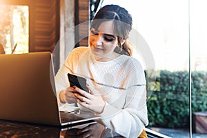 Girl browsing social networks on smartphone while sitting cafe. Blogger chatting with followers oncell phone coffee shop.Lifestyle