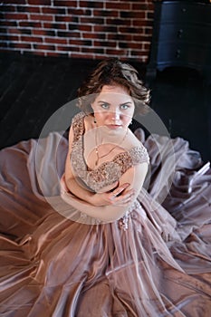 The girl the brunette in a beautiful dress poses sitting on a floor