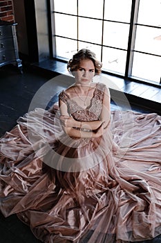 The girl the brunette in a beautiful dress poses sitting on a floor