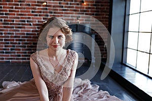 The girl the brunette in a beautiful dress poses sitting on a floor