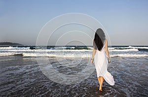 Girl brunette in white dress entering the Indian Ocean. photo