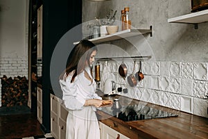 Girl brunette young woman in casual clothes standing at the stove, cooking in the kitchen at home