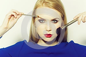 Girl with brushes applying makeup and powder on face