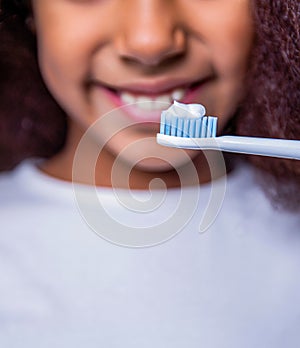 Girl brushing her teeth against a white background. Adorable african american kid brushing teeth. Little girl toothbrush