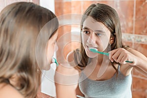 Girl brushing her teeth in front of a mirror