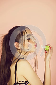 Girl with bubble blower on pink studio background