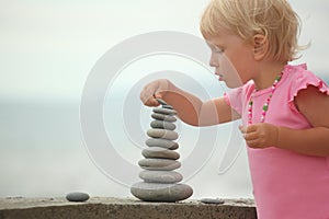 Girl is building a construction from pebble stones