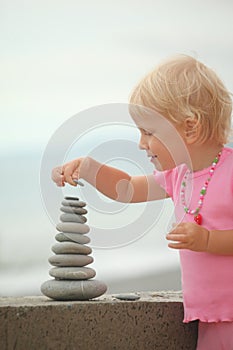 Girl is building a construction from pebble stones