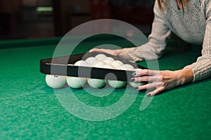 Girl builds a pyramid of balls in billiards. Woman playing in billiard