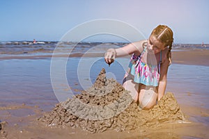 Girl is bulding sandcastles on the beach