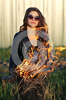 Girl bully standing in a black jacket is a fire in their hands Outdoors