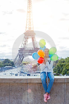 Girl with bunch of colorful balloons in Paris near the Eiffel tower.