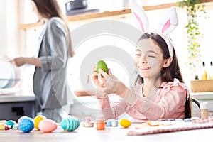 Girl with bunny ears having fun decorate Easter eggs.