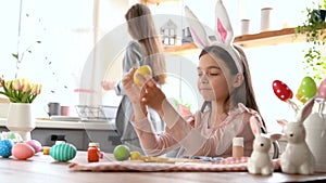 Girl with bunny ears having fun decorate Easter eggs.