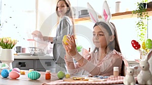 Girl with bunny ears having fun decorate Easter eggs.