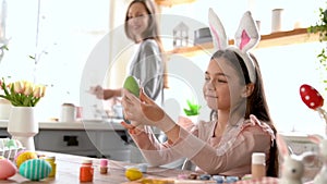 Girl with bunny ears having fun decorate Easter eggs.