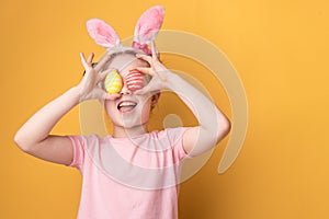 Girl with bunny ears holds painted Easter eggs