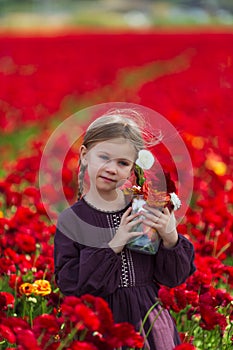 Girl in a burgundy summer dress picking flowers in the meadow