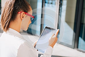 A girl businessman wearing glasses looks at the screen of her electronic tablet, the kind of shady woman who reads a letter online