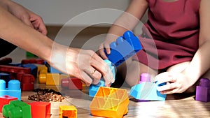 Girl busy with his building constructor bricks. Happy family playing educational toys at home
