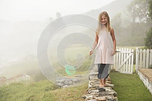Girl With Butterfly Net Balancing On Stone Wall