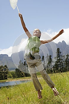 Girl With Butterfly Net Jumping In Field