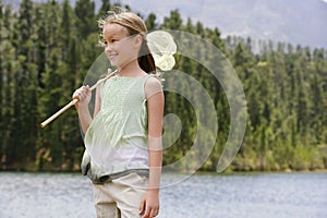 Girl With Butterfly Net Standing By Lake
