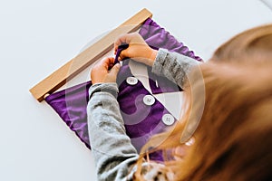 Girl buttoning a montessori frame to develop the dexterity of her fingers photo