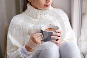 Girl with cacao mug looking at home window