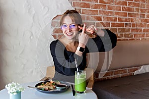 A girl in a cafe at breakfast shows various gestures with her hands