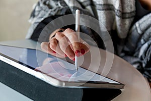 A girl in a cafe draws with a stylus on a graphics tablet