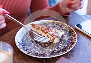 Girl in a cafe eats with a fork a piece of cake on a plate. focus on cake. breakfast, start of a new day