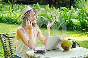 Girl at cafe talking by phone with client about photoshoot on vacation on beach