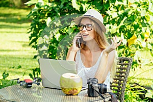 Girl at cafe talking by phone with client about photoshoot on vacation on beach