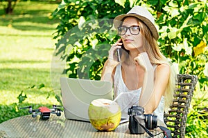 Girl at cafe talking by phone with client about photoshoot on vacation on beach