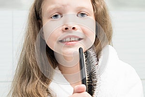 Girl calculated hair with a comb and sings in the bathroom