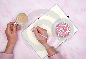 the girl calculates in a notebook the calories of a donut and a cup of coffee