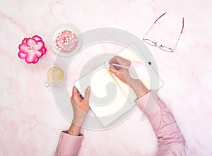 the girl calculates in a notebook the calories of a donut and a cup of coffee