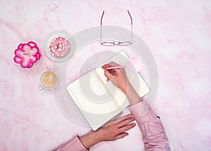 the girl calculates in a notebook the calories of a donut and a cup of coffee