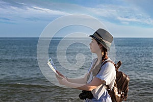 the girl with the camera, backpack and hat looking at the map